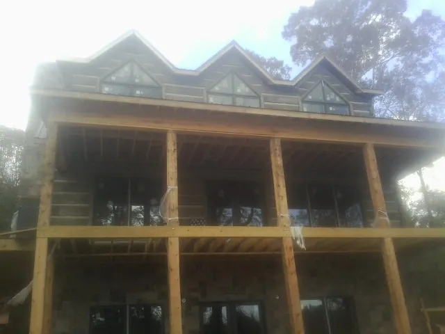 Dormers and porch framing on a large log home under construction — Roof Coating work by our crew in Bushnell