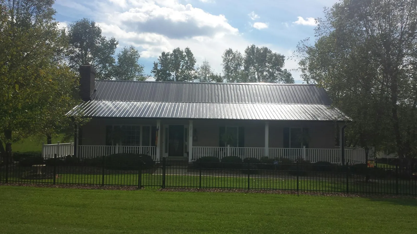 Gray metal roof on a brick ranch with a full width front porch — Gutter Guard Installation work by our crew in Bushnell