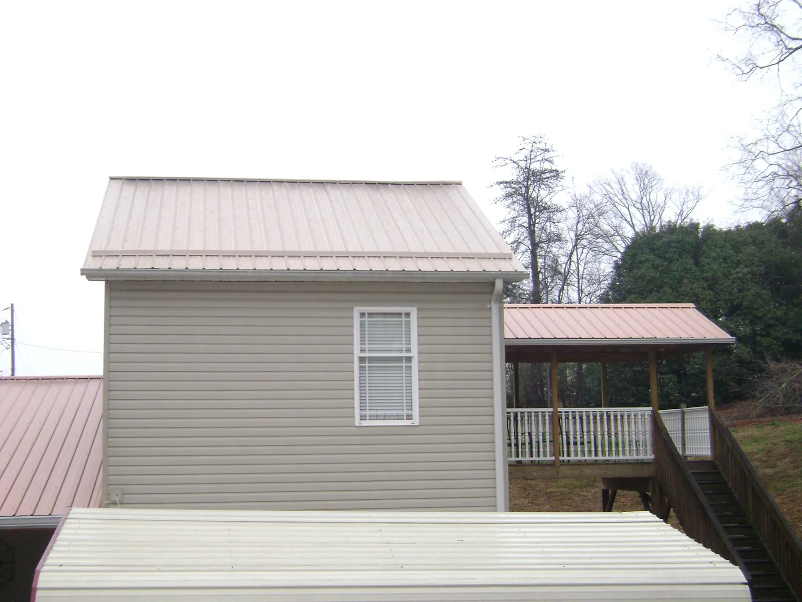 Tan metal roofs on a two story addition and attached porch, from a Roof Replacement job in Bushnell