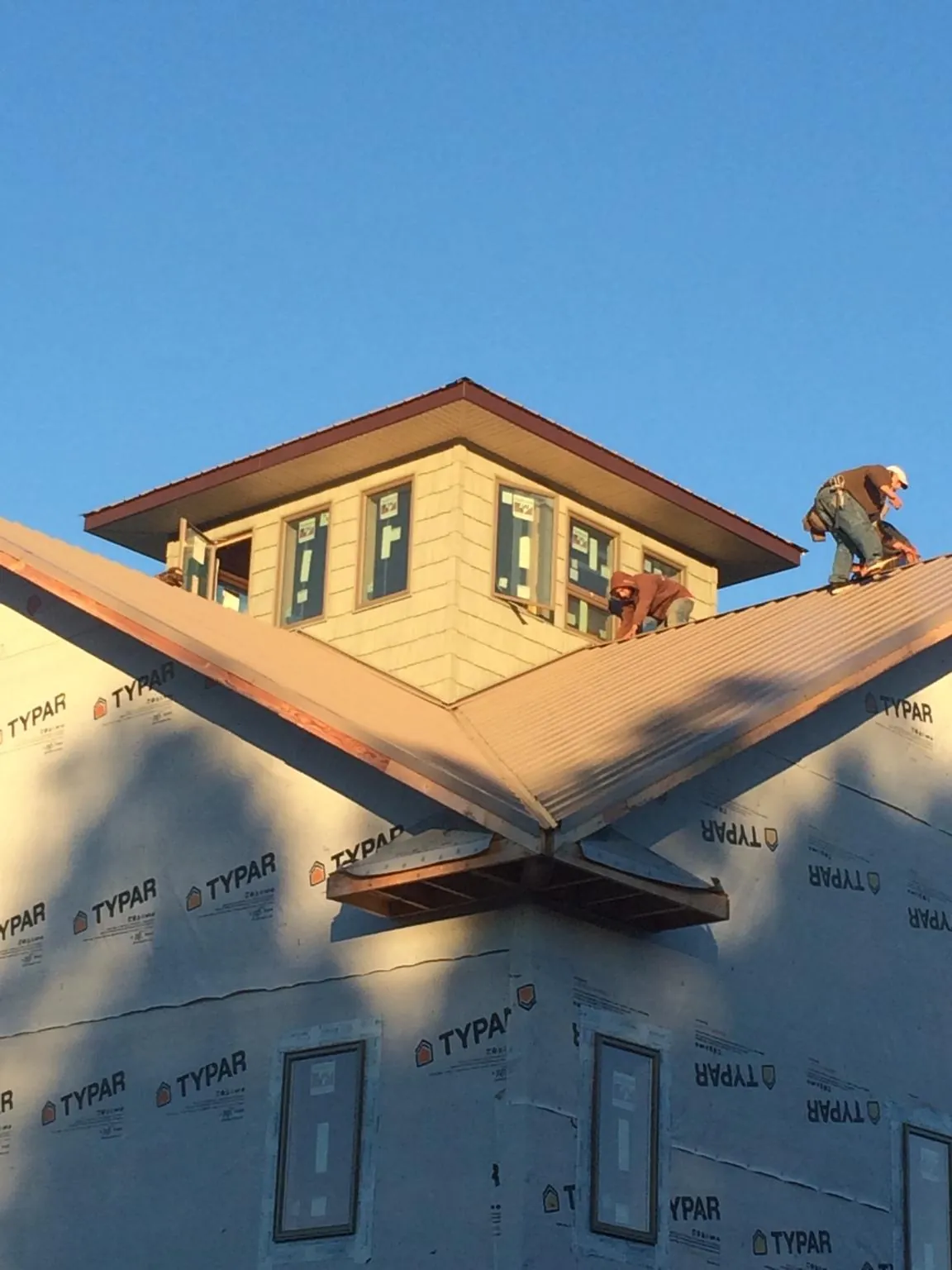Roofers working around a rooftop cupola on a new metal roof at sunset — Roof Waterproofing in Bushnell by Roofing Brothers